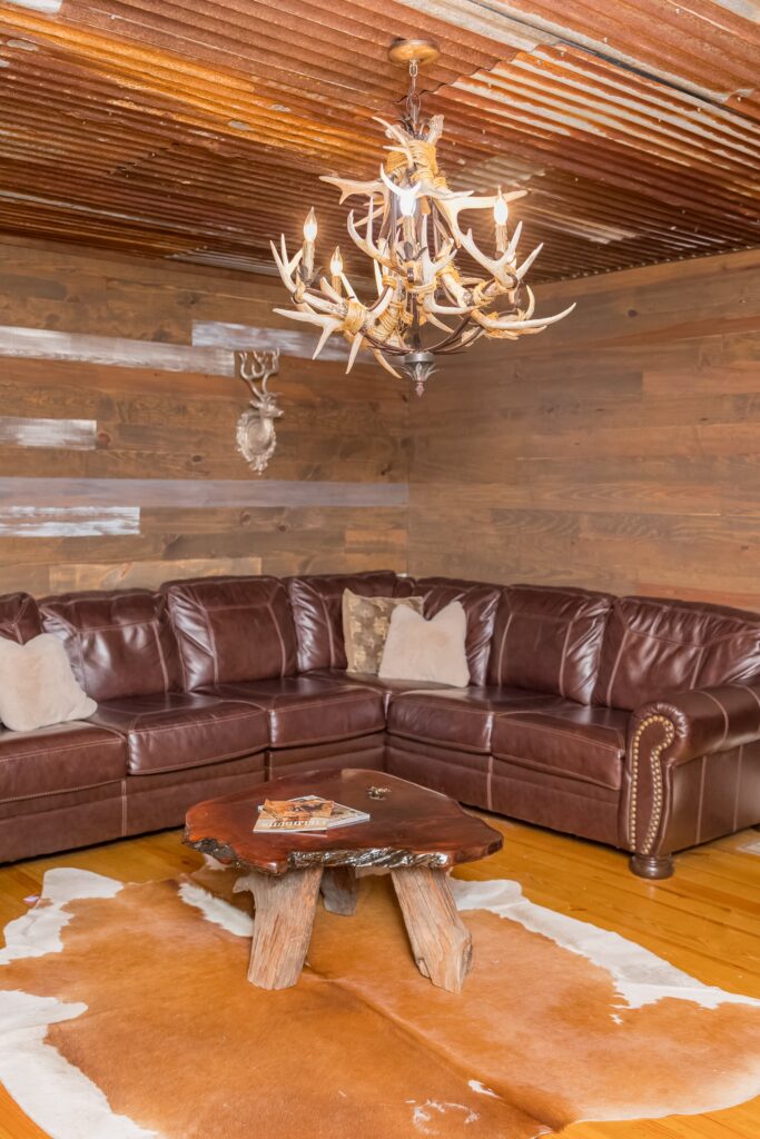 Rustic room for groom and groomsmen to prepare for wedding with leather couch and deer antler chandelier